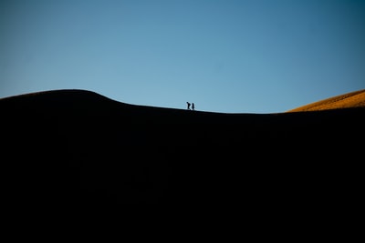 The silhouette of the day the man standing at the top of the mountain
